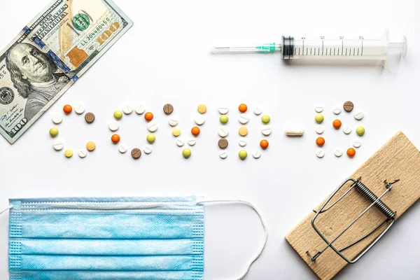Covid-19 inscription with pills with blue medical protective mask hundred dollar bill mousetrap and syringe in layout on white background copy space. Coronavirus, medicine and health, safety concept. — Stock Photo, Image