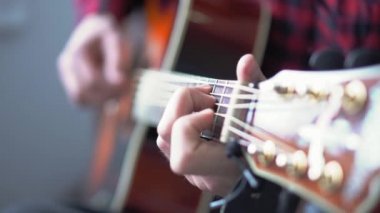 Müzik, yaratıcılık, konser, kendini izole etme konsepti. Akustik gitar radyosu çalan genç adamın yakın çekim elleri. Parmaklar dizgileri fretboard akorlarına basarak ayır.