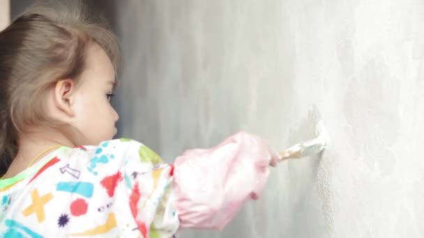 Reparação, renovação, casa, família, infância, paternidade, paternidade, auto-isolamento, conceito de quarentena - close-up pequena menina de 3 anos brincando com rolo, parede de pintura em apartamento tinta branca . — Vídeo de Stock