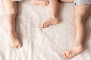 Çocukluk, uyku, rahatlama, aile, yaşam tarzı konsepti - bej bej beyaz bir ekose karşısında rastgele uzanan uyuyan çocukların ayakları