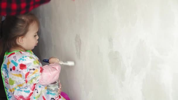 Réparation, rénovation, maison, famille, enfance, parentalité, paternité, auto-isolement, concept de quarantaine - plan rapproché petite fille de 3 ans jouant avec rouleau, peinture murale dans un appartement peinture blanche . — Video