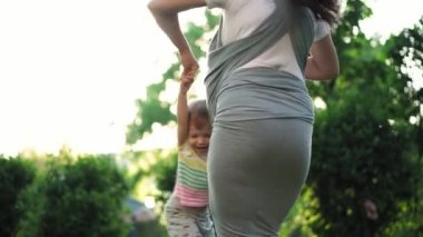 aile, çocuklar, annelik, eğlence ve insan konsepti. Birçok çocuğun kucağında bebekle kucak kucağa sallanan bir anne. Oğlunu kollarıyla parktaki günbatımının arka planında sallıyor..