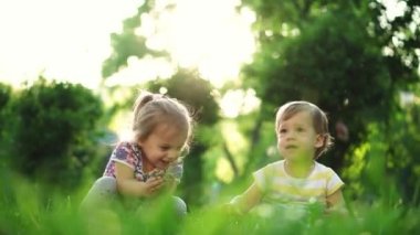 çocukluk, aile, yaşam tarzı, eğlence ve insan konsepti - aynı yaştaki iki küçük çocuk, bir oğlan ve bir kız çimenleri yırtıyor ve gün batımının arka planına doğru parka kusuyor.