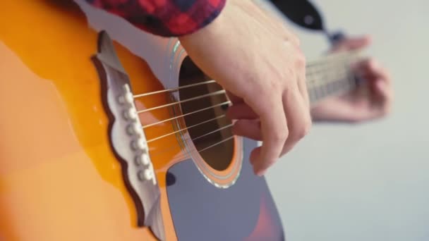 Musik, kreativitet, konsert, självisolering. Närbild händer ung man spelar en akustisk gitarr dreadnought i mjuk fokus. Fingrar sorterar ut strängar genom att trycka ackord på remmar av fretboard. — Stockvideo