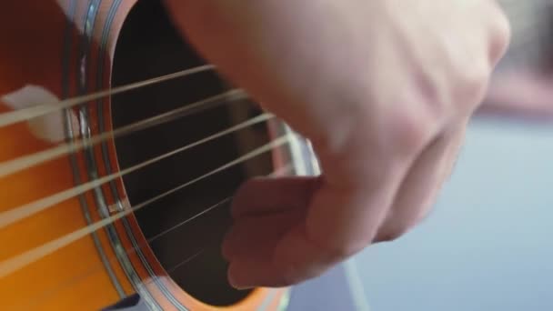 Musik, kreativitet, konsert, självisolering. Närbild händer ung man spelar en akustisk gitarr dreadnought i mjuk fokus. Fingrar sorterar ut strängar genom att trycka ackord på remmar av fretboard. — Stockvideo