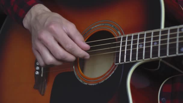 Muziek, creativiteit, concert, zelf-isolatie concept. Close-up handen van de jongeman die een akoestische gitaar dreadnought speelt in zachte focus. Vingers sorteren snaren door akkoorden te drukken op frets van fretboard. — Stockvideo