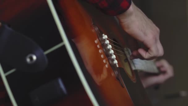 Musik, kreativitet, konsert, självisolering. Närbild händer ung man spelar en akustisk gitarr dreadnought i mjuk fokus. Fingrar sorterar ut strängar genom att trycka ackord på remmar av fretboard. — Stockvideo