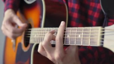 Müzik, yaratıcılık, konser, kendini izole etme konsepti. Akustik gitar radyosu çalan genç adamın yakın çekim elleri. Parmaklar dizgileri fretboard akorlarına basarak ayır.