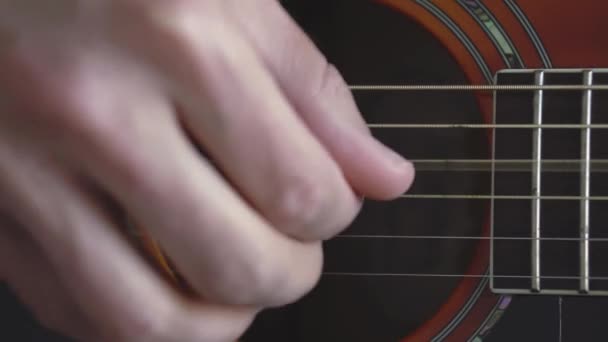 Musik, kreativitet, konsert, självisolering. Närbild händer ung man spelar en akustisk gitarr dreadnought i mjuk fokus. Fingrar sorterar ut strängar genom att trycka ackord på remmar av fretboard. — Stockvideo