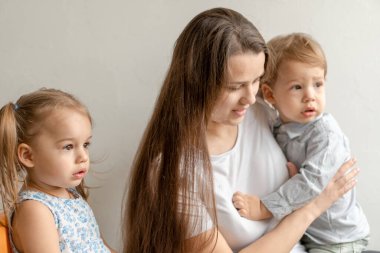 Annelik, anneler günü, doğum günü, çocukluk, aile konsepti - küçük çocuklar erkek ve kız tebrik eder ve genç anneye beyaz arka planda büyük bir buket sarı papatya çiçeği verir.