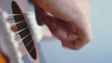 Müzik, yaratıcılık, konser, kendini izole etme konsepti. Akustik gitar radyosu çalan genç adamın yakın çekim elleri. Parmaklar dizgileri fretboard akorlarına basarak ayır.