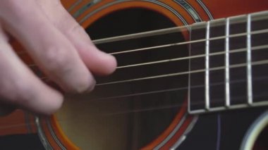 Müzik, yaratıcılık, konser, kendini izole etme konsepti. Akustik gitar radyosu çalan genç adamın yakın çekim elleri. Parmaklar dizgileri fretboard akorlarına basarak ayır.