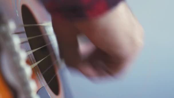 Hudba, tvořivost, koncert, koncepce sebeizolace. Detailní záběr rukou mladého muže hrajícího na akustickou kytaru v měkkém ohnisku. Prsty třídí struny stiskem akordů na prknech prkna. — Stock video