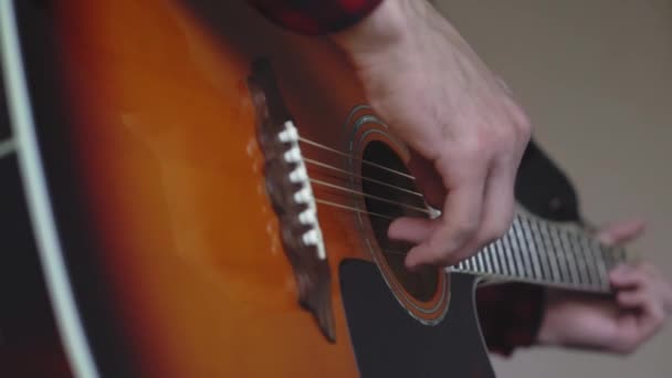 Muziek, creativiteit, concert, zelf-isolatie concept. Close-up handen van de jongeman die een akoestische gitaar dreadnought speelt in zachte focus. Vingers sorteren snaren door akkoorden te drukken op frets van fretboard. — Stockvideo