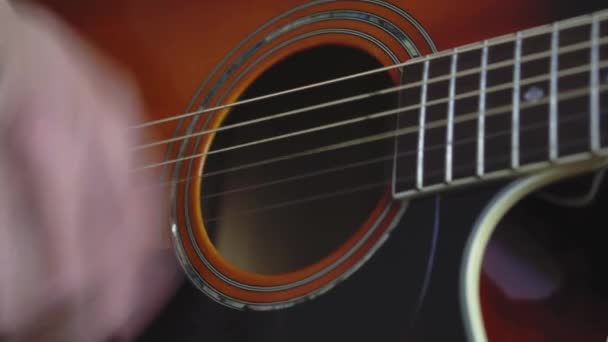 Musik, kreativitet, konsert, självisolering. Närbild händer ung man spelar en akustisk gitarr dreadnought i mjuk fokus. Fingrar sorterar ut strängar genom att trycka ackord på remmar av fretboard. — Stockvideo