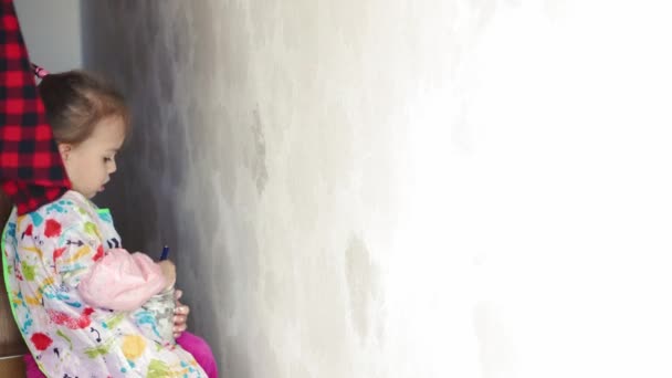 Reparación, renovación, hogar, familia, infancia, paternidad, paternidad, autoaislamiento, concepto de cuarentena: primer plano niña de 3 años jugando con el rodillo, pintando la pared en la pintura blanca del apartamento . — Vídeos de Stock