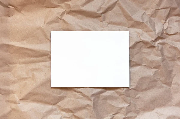 Crumpled craft brown paper background with white sheet in middle. Copy space. Horizontal. DIY, handicraft, back to school, ecology, plastic free concept, harvesting for mock up. Flat lay, top view — 스톡 사진