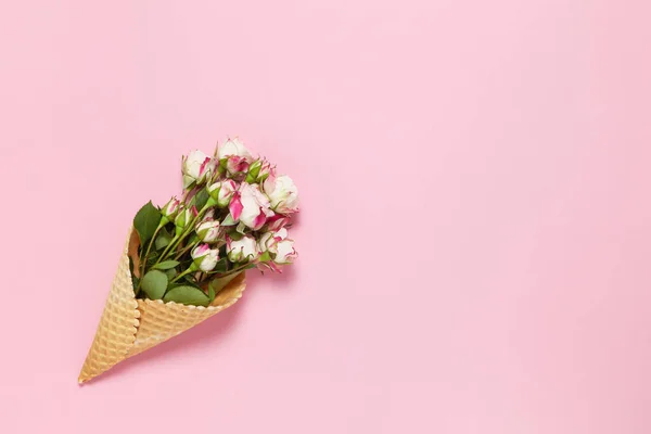 Pembe arka planda waffle külahında küçük güller, kopyalama alanı. Minimal stil düz. Tebrik kartı için davetiye. 8 Mart, 14 Şubat, doğum günü, sevgililer günü, anneler, kadınlar günü konsepti. Üst görünüm