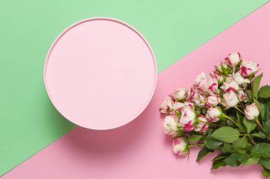 Pembe yuvarlak hediye kutusu, pastel renkli iki renkli arka plan pembe ve yeşil gül buketi, fotokopi alanı, düz yatak. 8 Mart, 14 Şubat, Sevgililer Günü, Anneler, Kadınlar Günü Kutlama Konsepti