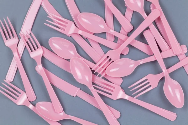 背景为可重复使用的粉红叉子、勺子、用玉米淀粉在灰纸上制成的刀具。生态，零废物，塑料概念的替代品。平躺在地上，尽收眼底。横向的。包扎 — 图库照片