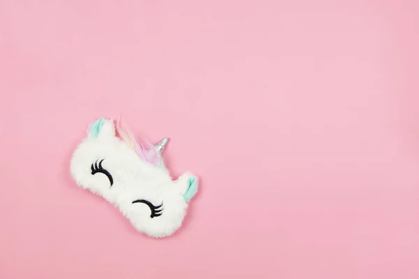 Beyaz tüylü, tüylü, tek boynuzlu at, gözleri kapalı, kulakları pastel pembe kağıt arka planda, kopyalama alanı. Üst manzara, düz yatış. Gerçekçi rüyalar kavramı. Kızlar ve genç kadınlar için aksesuarlar.