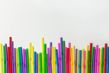 İçecekler için tek kullanımlık plastik borular beyaz arka planda sıraya dizilmiş, kopyalama alanı. Şenlik konsepti, parti, doğum günü. Düz yerde, üst tarafta. Yatay.