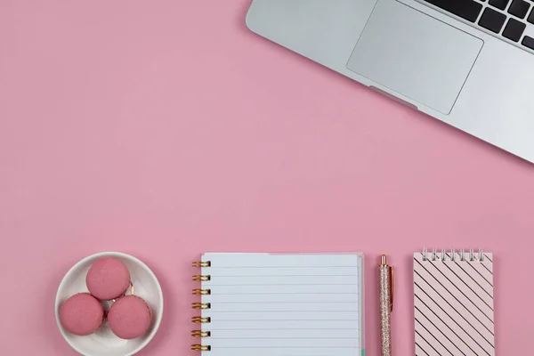Modern kadın çalışma alanı, üst görünüm. Laptop, dizüstü bilgisayarlar, gül sarısı kalemler, pembe arka planda badem kurabiyeleri, fotokopi alanı, düz yatak. Blogcu masası, serbest yazar. Ev kavramından çalış. Yatay.