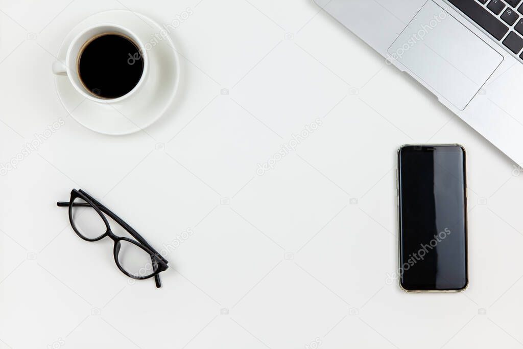 Modern working space, top view. Laptop, coffee, smart phone, glasses on white background, copy space, flat lay. Desktop of freelancer. Work from home, stay home, using technology concept.