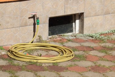 Bahçe hortumu kaldırımda ot ve kirli eski rüzgar ile döşeme