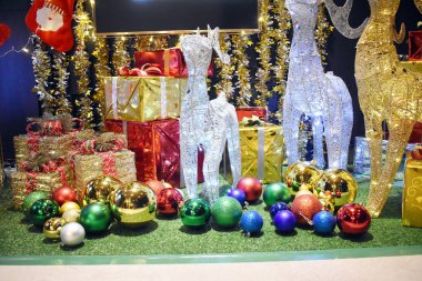 Gümüş ve altın renginde geyik Noel süsleri, güzel hediye kutuları ve yeşil zeminde renkli toplar.