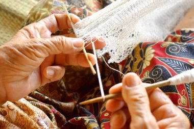 Yaşlı kadınlar kırsalda bir balık ağı (dip-net) örerler.