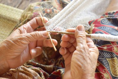 Yaşlı kadınlar kırsalda bir balık ağı (dip-net) örerler.