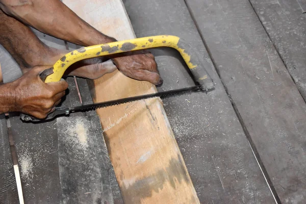 Man sawing wood by using a hand wood saw in countryside of Thailand