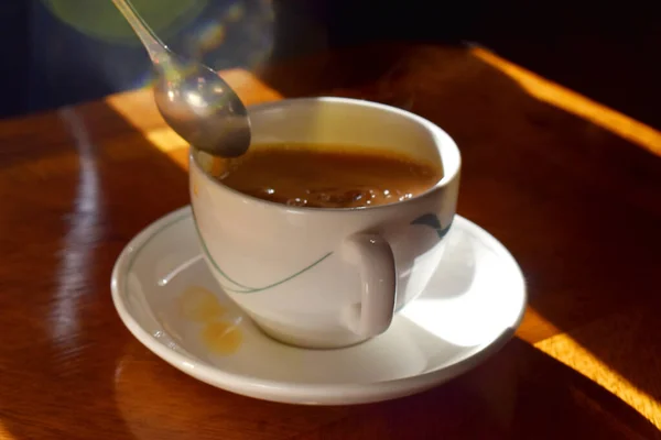 Çay kaşığı çay fincanının üstünde sütlü, ahşap masaya konmuş, öğleden sonra geleneksel İngiliz çayı..