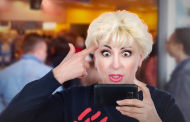 Rahatsız sarışın kadın video çağrısı tarafından cep telefonu bulunuyor.
