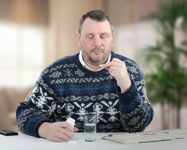 Mature man looks at the white pill thoughtfully — Stock Photo, Image