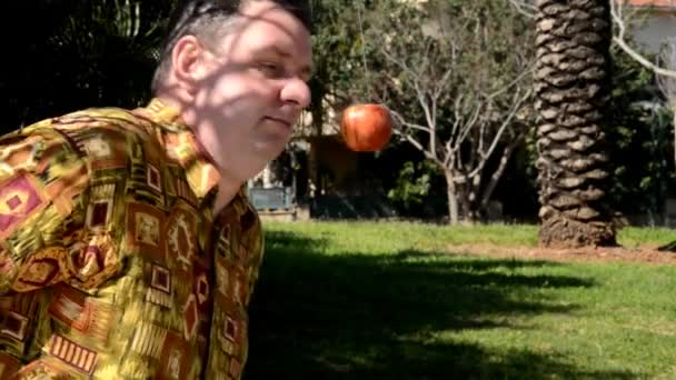 Hombre con camisa de aloha intenta morder manzana colgante — Vídeos de Stock