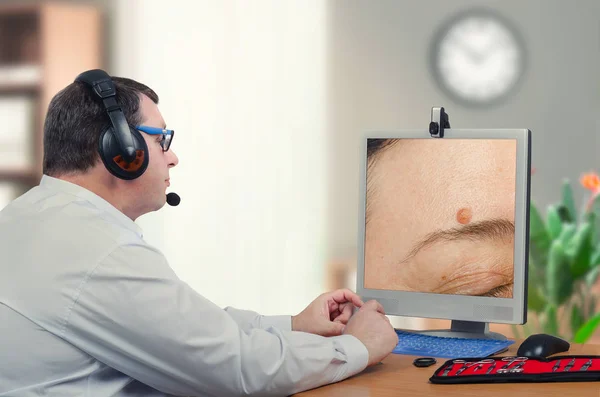 Telemedicine dermatologist examines mole above eyebrow — Stock Photo, Image