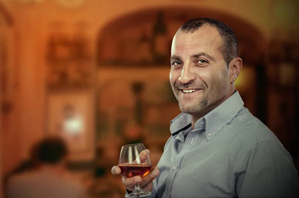 Lachende volwassen man poseren met glas cognac — Stockfoto