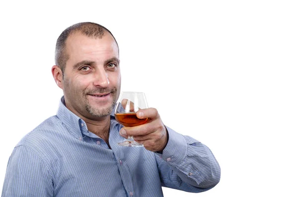 Мужчина в полосатой рубашке держит стакан бренди — стоковое фото