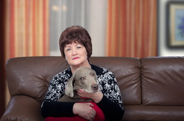 Older woman posing with dog on leather couch — Stock Photo, Image