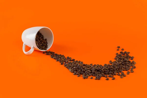 Café en una taza blanca sobre fondo naranja con granos de café . —  Fotos de Stock