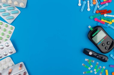 Glukometre. Kan şekeri seviyelerini ölçen bir cihaz. Test bantları, mavi arka planda haplar..