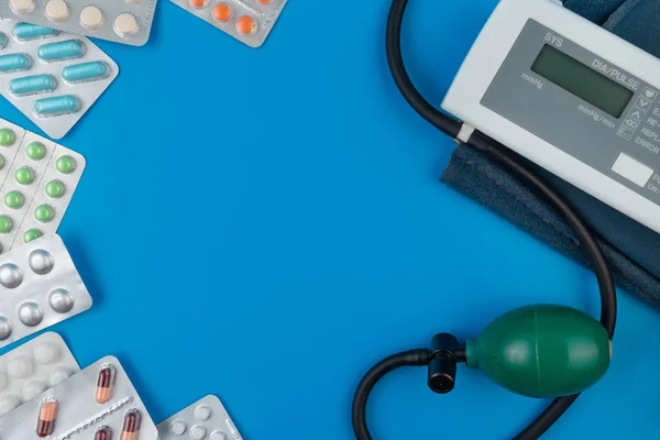 Elektronisches Tonometer, ein Gerät zur Druckmessung. Farbtabletten. Spritzen mit dem Medikament. blauer Hintergrund. — Stockfoto