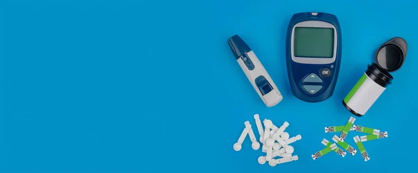 Glucometer. Пристрій для вимірювання рівня цукру в крові. Тестові смуги, таблетки на синьому фоні.. — стокове фото