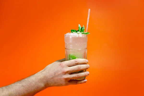 紧紧地握住一个男人的手 手里拿着一杯带橙色背景的热带莫吉托鸡尾酒 还有复制的空间 暑假的概念 — 图库照片