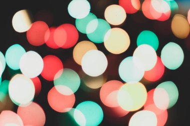 Odaklanamayan parlak renkli yeni yıl ışıkları koyu bulanık arkaplanda