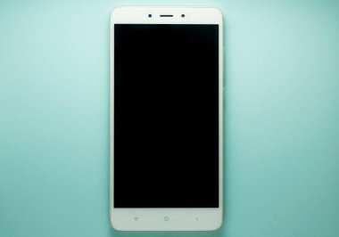 Mavi yüzeyde boş ekran ve kopyalama alanı olan beyaz akıllı telefonun üst görünümü 