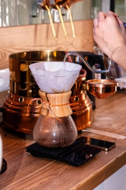 Cherkassy, Ukrayna, Brewlove cafe, 08.14.2019: Kafedeki akıllı telefonun yanındaki ahşap masaya kahve ve kahve ile cam mataraya su döken kadın görüntüsü