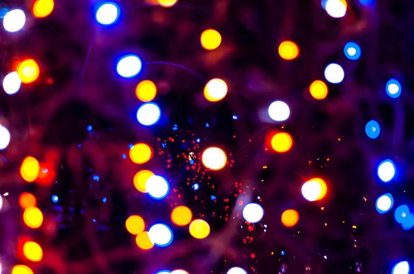 blurred unfocused multicolored christmas lights with sparkle on dark background with bokeh effect for wallpaper and design